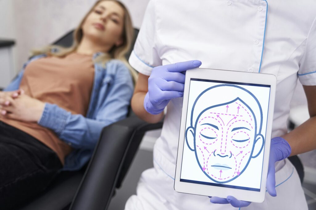 Doctor presenting digital tablet with face lifting sketch