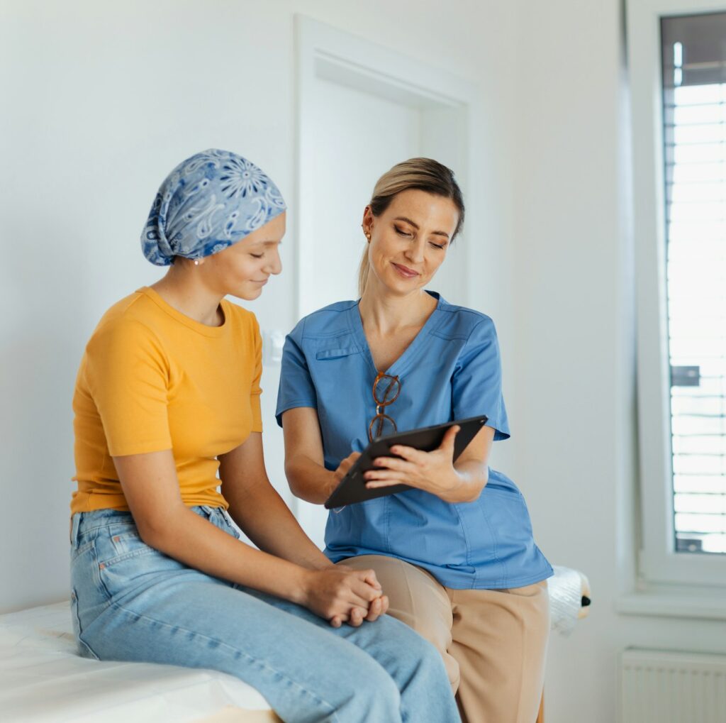 Teenage oncology patient talking with doctor. Oncologist treating teen girl with cancer and provide